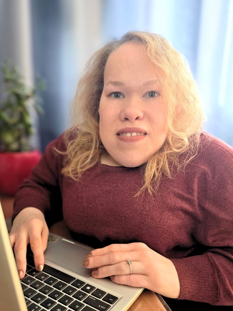 Bloga "Digitālā Lapsa" autore Elīna strādā ar datoru, skatiens kamerā